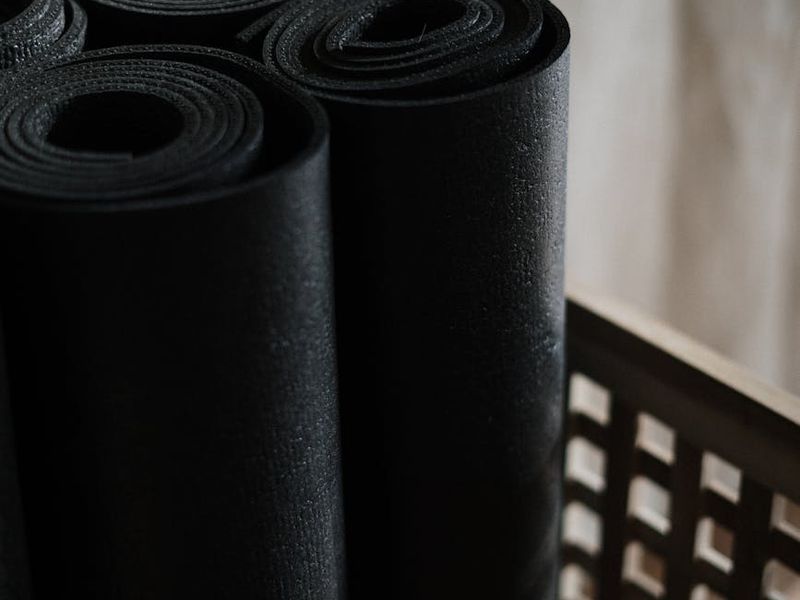 Close up of yoga equipment on a dark wooden floor.
