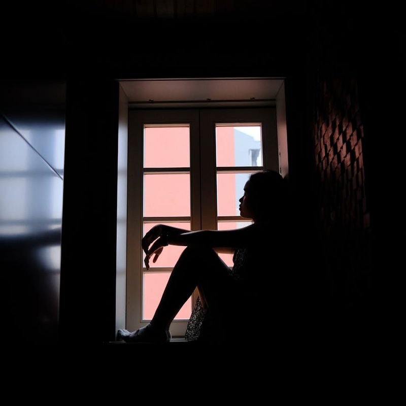 Person doing a peaceful sitting meditation in a dark room.